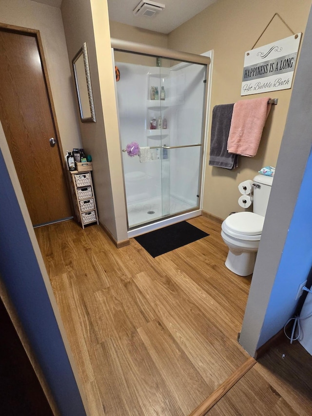 full bath with toilet, a shower stall, visible vents, and wood finished floors