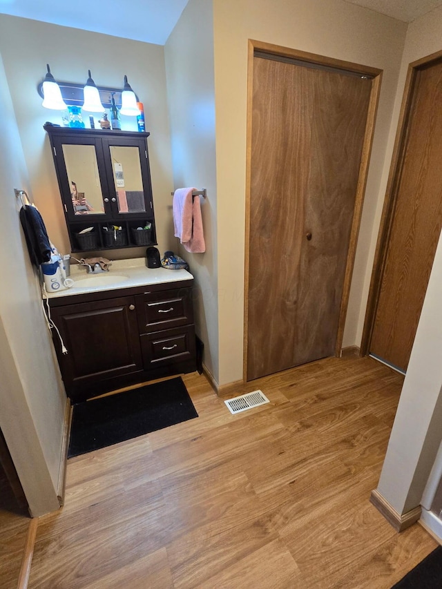 bathroom with vanity, wood finished floors, visible vents, and baseboards