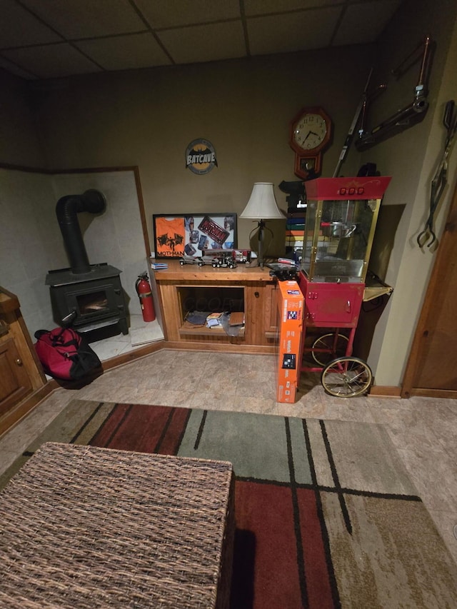 living area with a drop ceiling and a wood stove