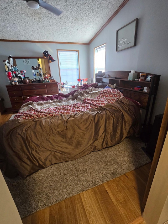 bedroom with lofted ceiling, ornamental molding, ceiling fan, a textured ceiling, and wood finished floors