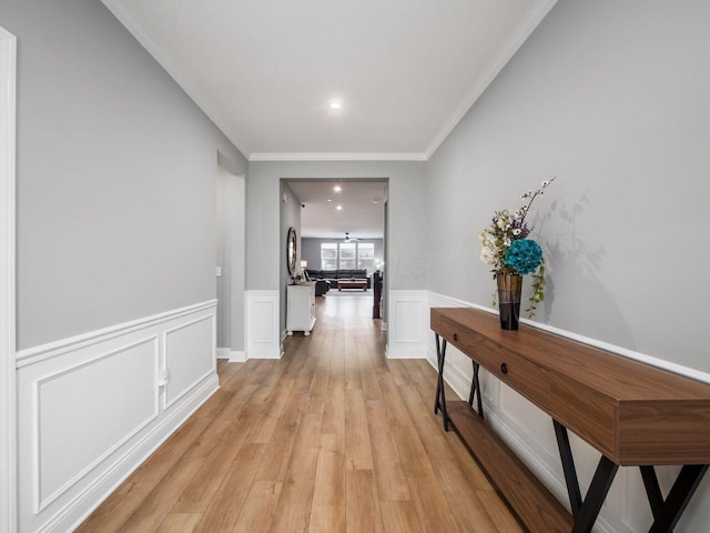 hallway with ornamental molding and light hardwood / wood-style flooring