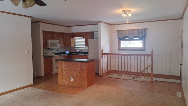 kitchen with white appliances, a center island, ornamental molding, and sink