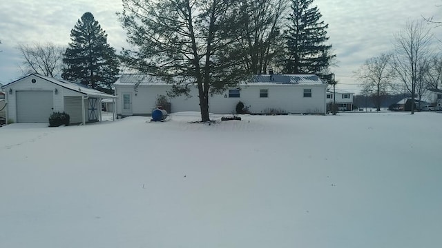 yard layered in snow with an outdoor structure and a garage