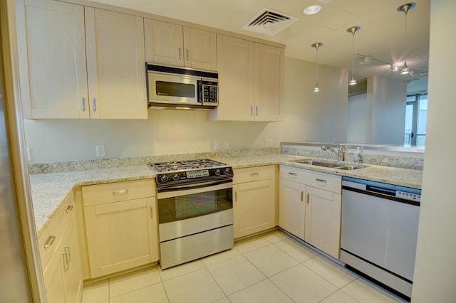 kitchen featuring pendant lighting, light stone countertops, sink, and stainless steel appliances