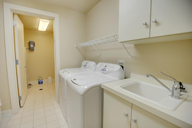 laundry room with cabinets, light tile patterned floors, washing machine and dryer, and sink