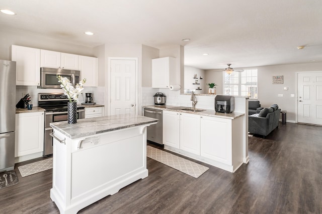 kitchen featuring white cabinets, a center island, light stone counters, and appliances with stainless steel finishes