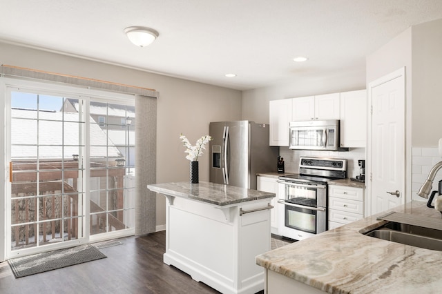 kitchen with white cabinetry, light stone counters, a center island, decorative backsplash, and stainless steel appliances