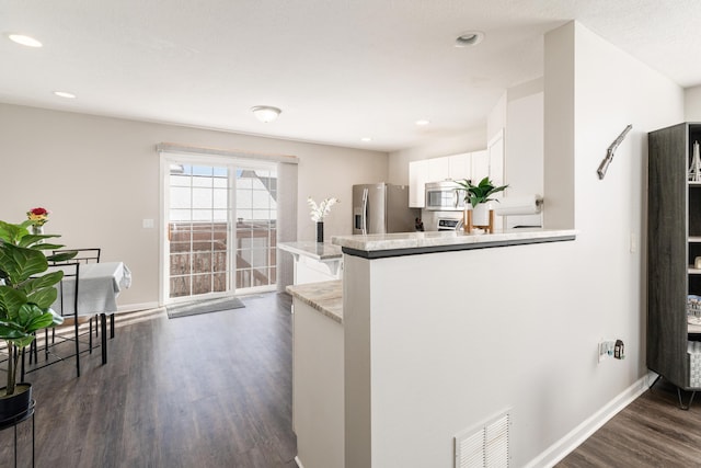 kitchen featuring white cabinets, dark hardwood / wood-style flooring, kitchen peninsula, and stainless steel appliances