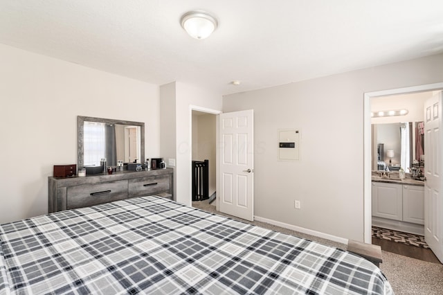 carpeted bedroom featuring sink, ensuite bathroom, and electric panel