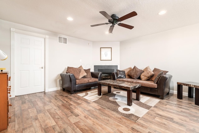 living room featuring a textured ceiling, light hardwood / wood-style flooring, and ceiling fan