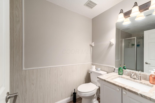 bathroom with a shower with shower door, a textured ceiling, toilet, and vanity