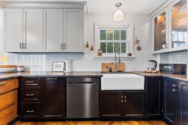 kitchen featuring dark stone counters, stainless steel dishwasher, tasteful backsplash, and sink