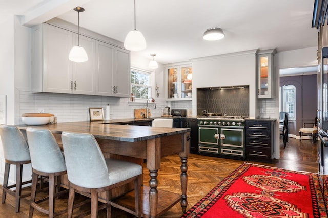 kitchen featuring white cabinets, hanging light fixtures, a breakfast bar, dark parquet flooring, and tasteful backsplash