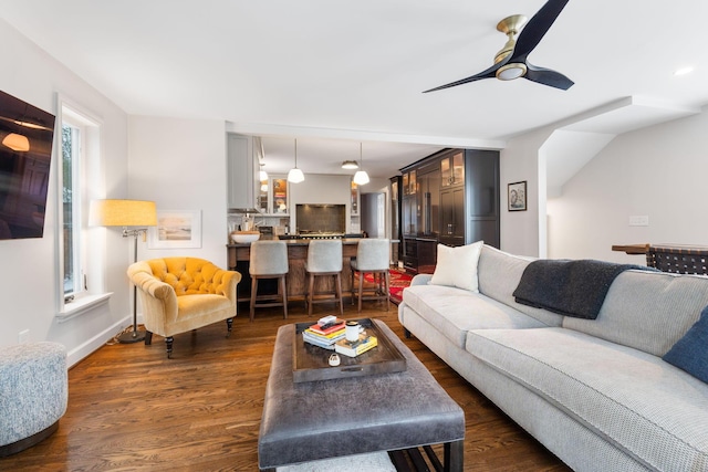 living room featuring dark wood-type flooring and ceiling fan