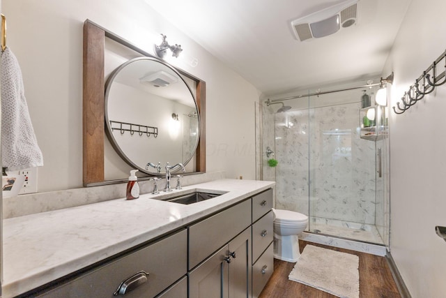 bathroom featuring hardwood / wood-style floors, toilet, vanity, and a shower with shower door