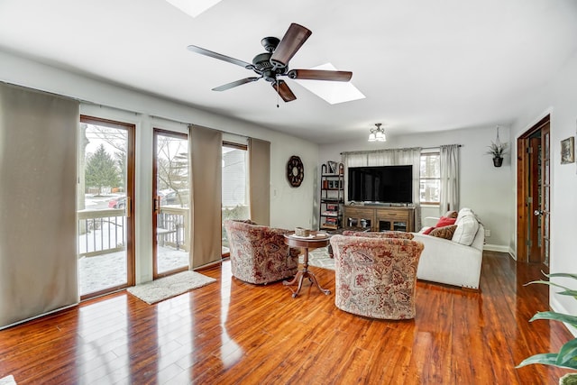 living room with wood-type flooring, a skylight, and ceiling fan