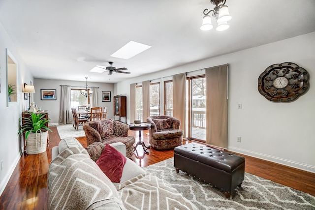 living room featuring ceiling fan with notable chandelier, a skylight, and wood-type flooring