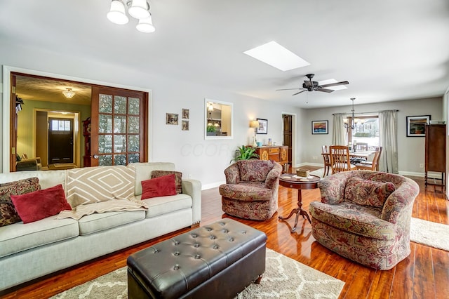 living room with a skylight, hardwood / wood-style floors, and ceiling fan with notable chandelier