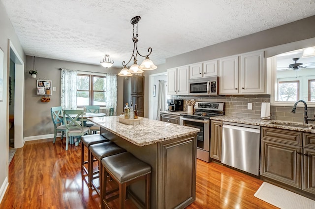 kitchen featuring stainless steel appliances, sink, a center island, a textured ceiling, and tasteful backsplash