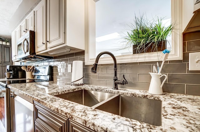 kitchen with appliances with stainless steel finishes, backsplash, and sink