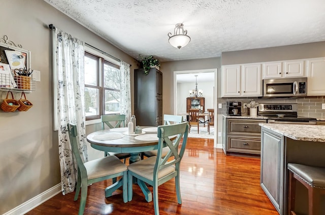 dining space featuring a textured ceiling, light wood-type flooring, and a notable chandelier