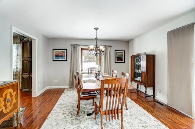 dining space with dark hardwood / wood-style flooring and an inviting chandelier