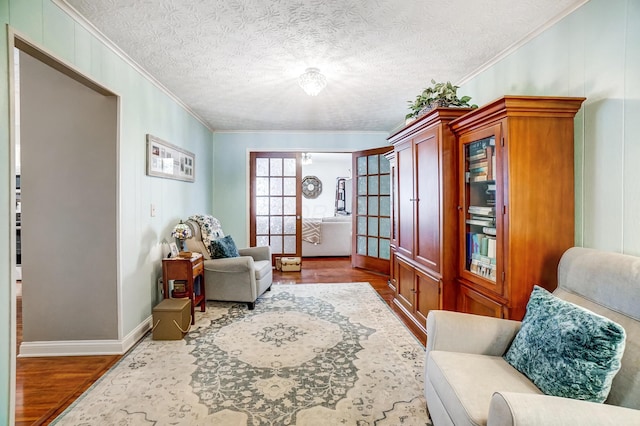 living area featuring wood-type flooring, a textured ceiling, and crown molding