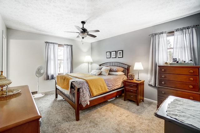 bedroom featuring ceiling fan, light carpet, and a textured ceiling