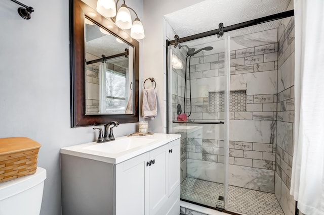 bathroom featuring toilet, a shower with shower door, and vanity