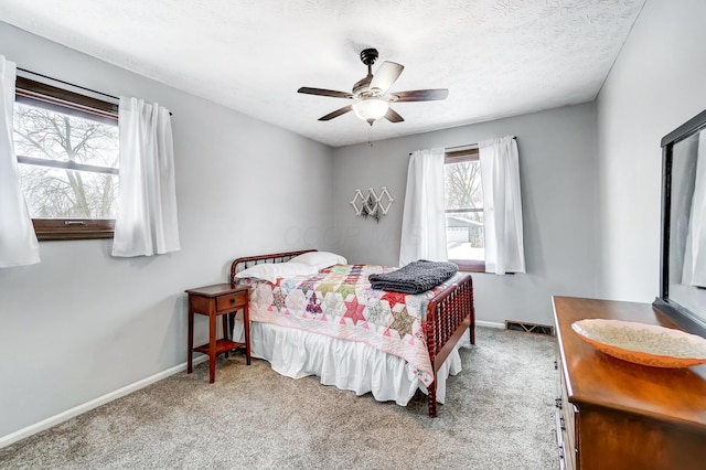 carpeted bedroom with ceiling fan and a textured ceiling