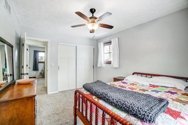 bedroom with a textured ceiling, ceiling fan, light carpet, and multiple windows