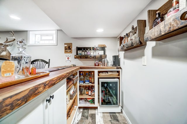 bar featuring butcher block counters, light hardwood / wood-style floors, and wine cooler