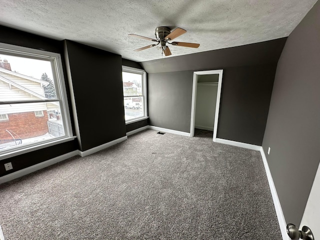 unfurnished bedroom with ceiling fan, carpet, a closet, a textured ceiling, and vaulted ceiling