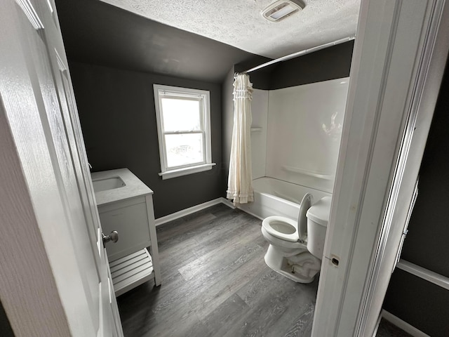 full bathroom with a textured ceiling, vanity, hardwood / wood-style flooring, toilet, and shower / bath combo with shower curtain