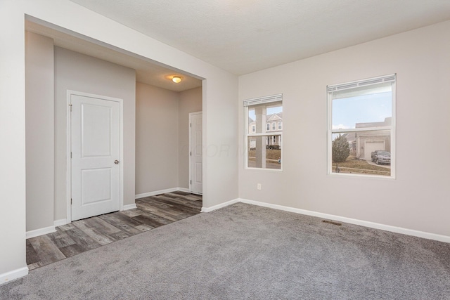 spare room featuring carpet flooring and baseboards