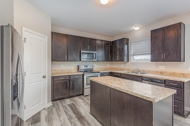 kitchen featuring appliances with stainless steel finishes, a sink, dark brown cabinetry, and light wood-style floors