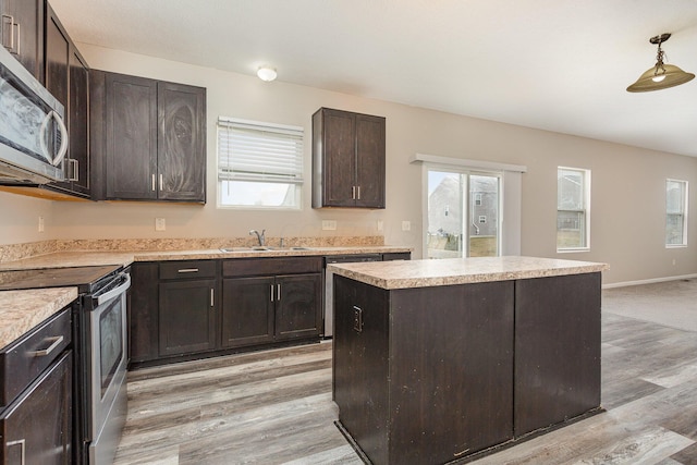 kitchen with light wood-style flooring, stainless steel appliances, dark brown cabinets, light countertops, and a sink