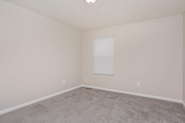 carpeted spare room with visible vents and baseboards