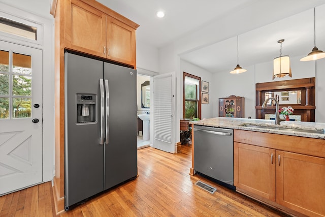 kitchen featuring light hardwood / wood-style floors, light stone counters, stainless steel appliances, and hanging light fixtures