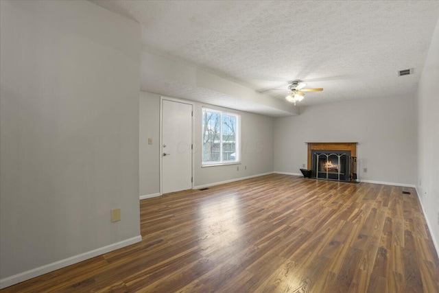 unfurnished living room featuring ceiling fan, a textured ceiling, and dark hardwood / wood-style flooring