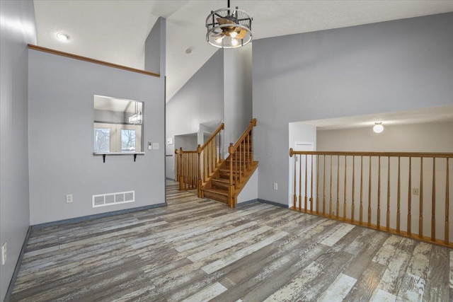 unfurnished living room featuring high vaulted ceiling, a notable chandelier, and hardwood / wood-style flooring