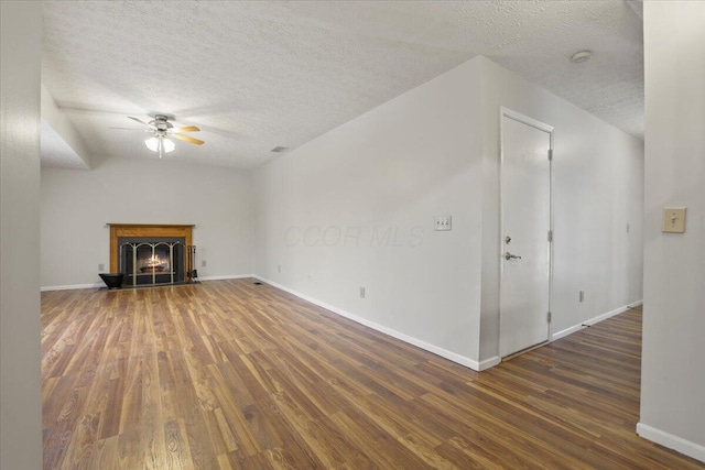 unfurnished living room featuring ceiling fan, dark hardwood / wood-style floors, and a textured ceiling