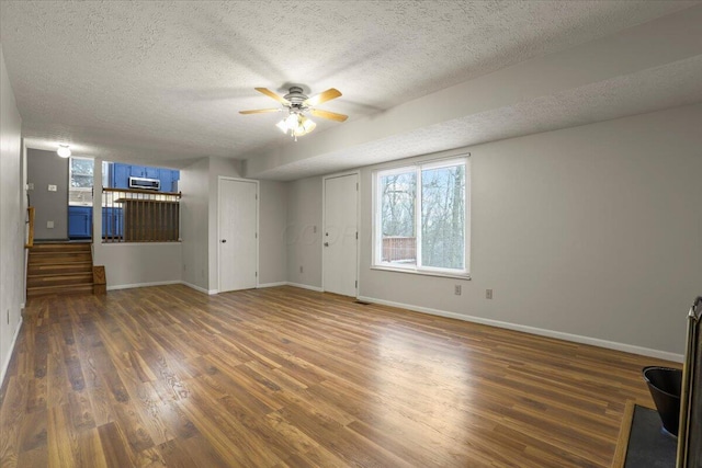 unfurnished living room featuring ceiling fan, a textured ceiling, and dark hardwood / wood-style floors