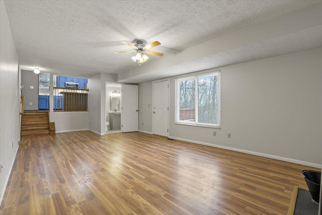 unfurnished living room featuring ceiling fan, dark hardwood / wood-style flooring, and a textured ceiling