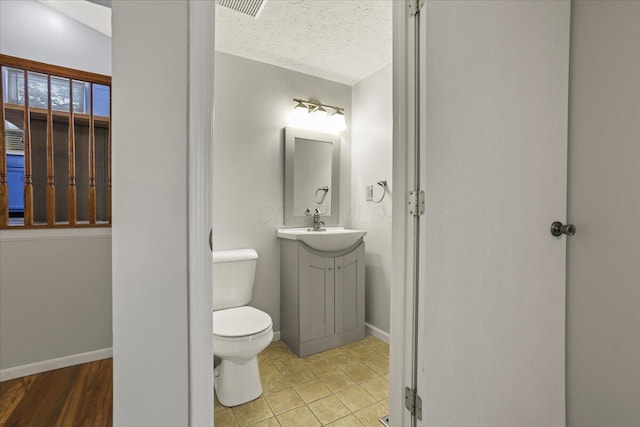 bathroom with a textured ceiling, toilet, and vanity