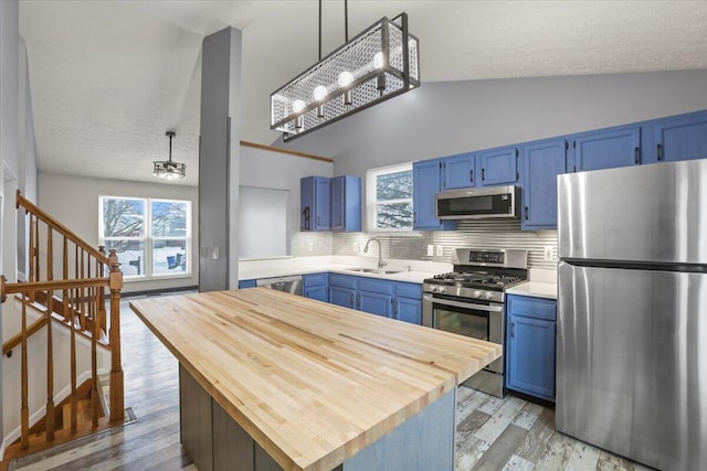 kitchen featuring decorative backsplash, blue cabinetry, appliances with stainless steel finishes, and sink