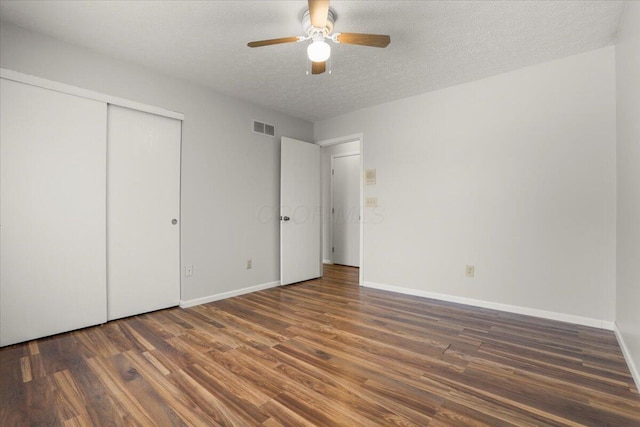 unfurnished bedroom with a textured ceiling, ceiling fan, a closet, and dark hardwood / wood-style floors