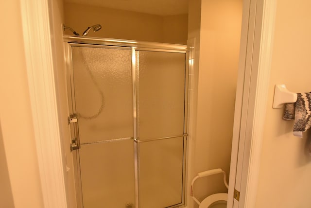 bathroom featuring toilet and a shower with shower door