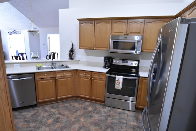 kitchen featuring sink, stainless steel appliances, hanging light fixtures, and vaulted ceiling