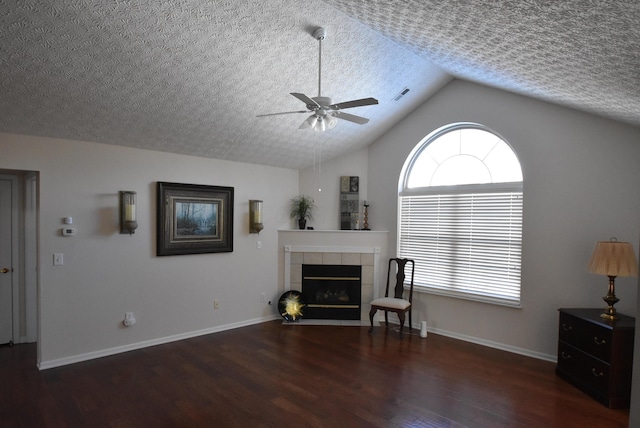 unfurnished living room with a tile fireplace, ceiling fan, dark hardwood / wood-style floors, a textured ceiling, and vaulted ceiling